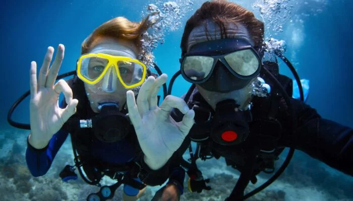 Two people Scuba Diving signaling ok under water... in New York